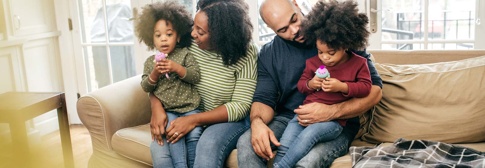 Parents and two young kids on couch at home.