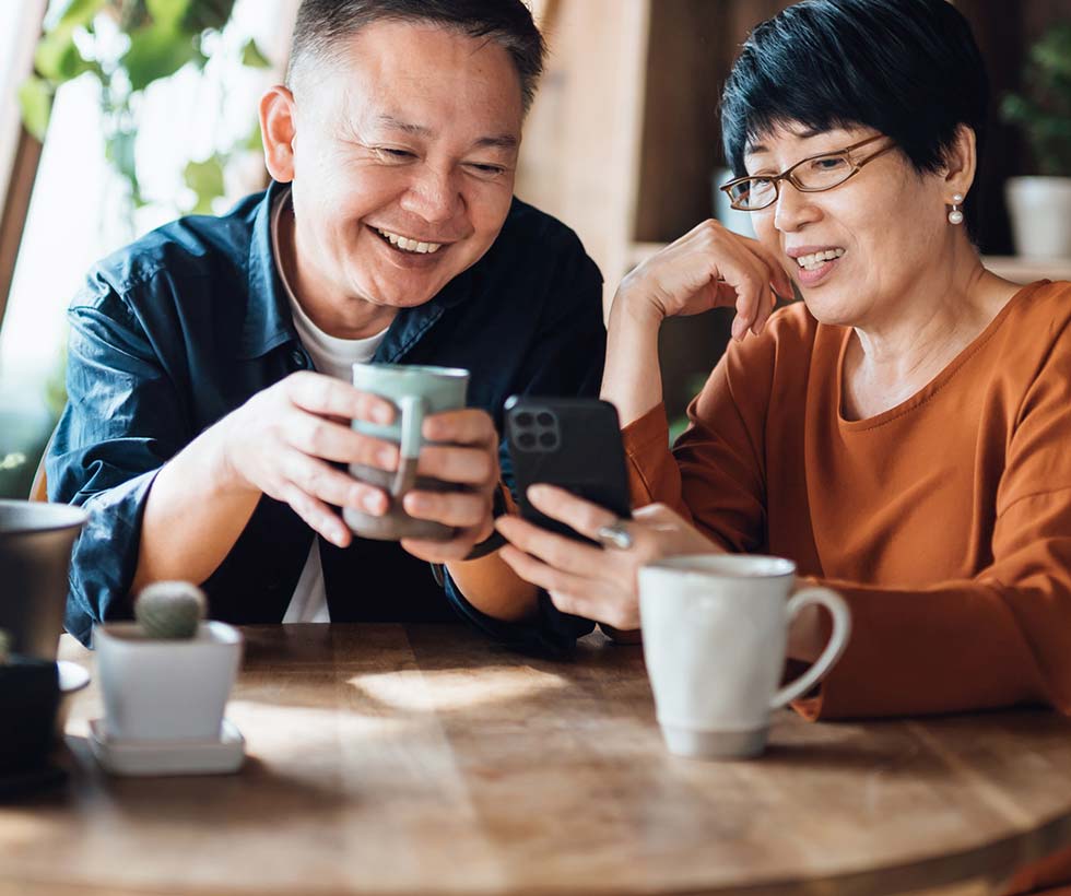 Mature couple having coffee, looking at phone